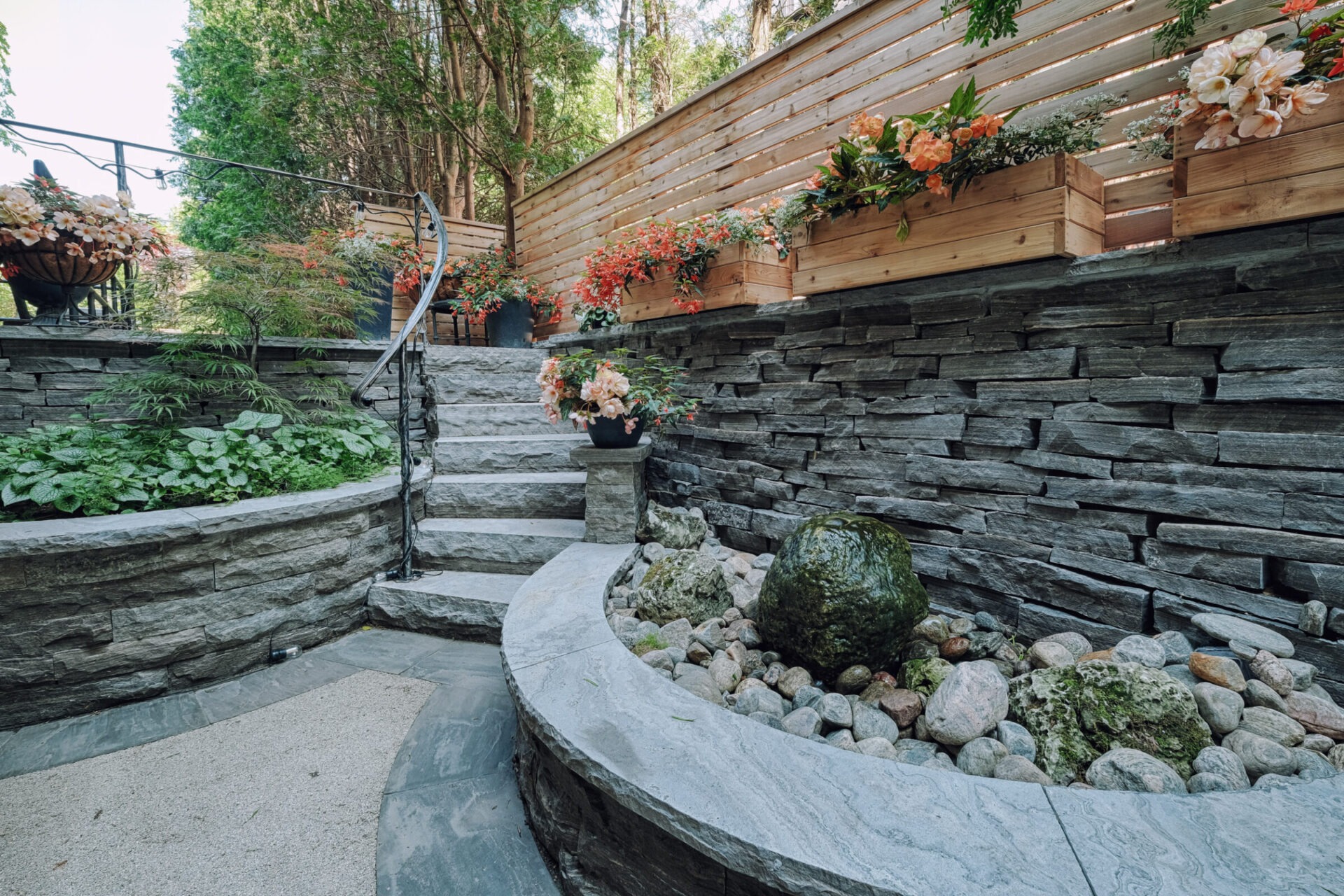 A serene garden staircase lined with stone walls and wooden planters filled with lush plants and bright flowers. Curved steps lead to a tranquil area.