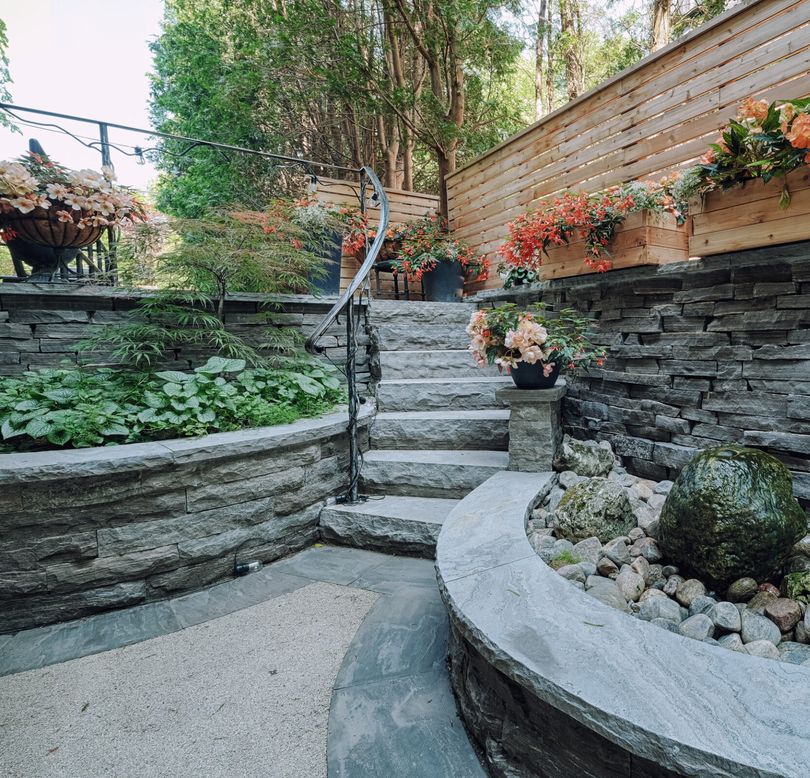 A serene garden staircase lined with stone walls and wooden planters filled with lush plants and bright flowers. Curved steps lead to a tranquil area.