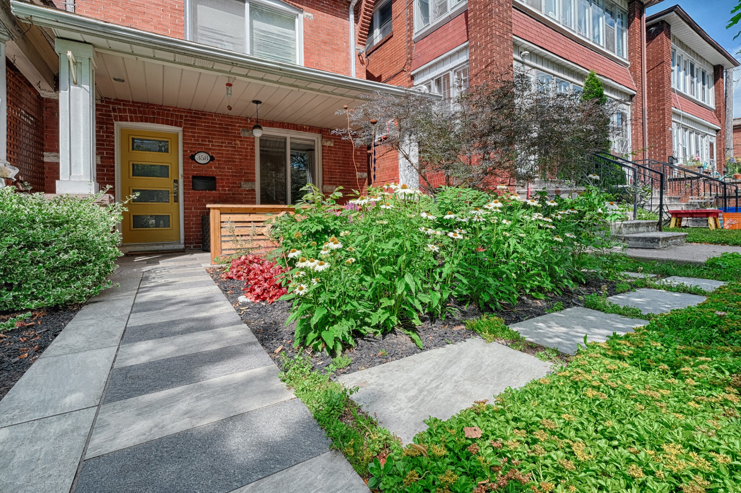 Front yard landscaping in Toronto featuring some stone paths and bushes.
