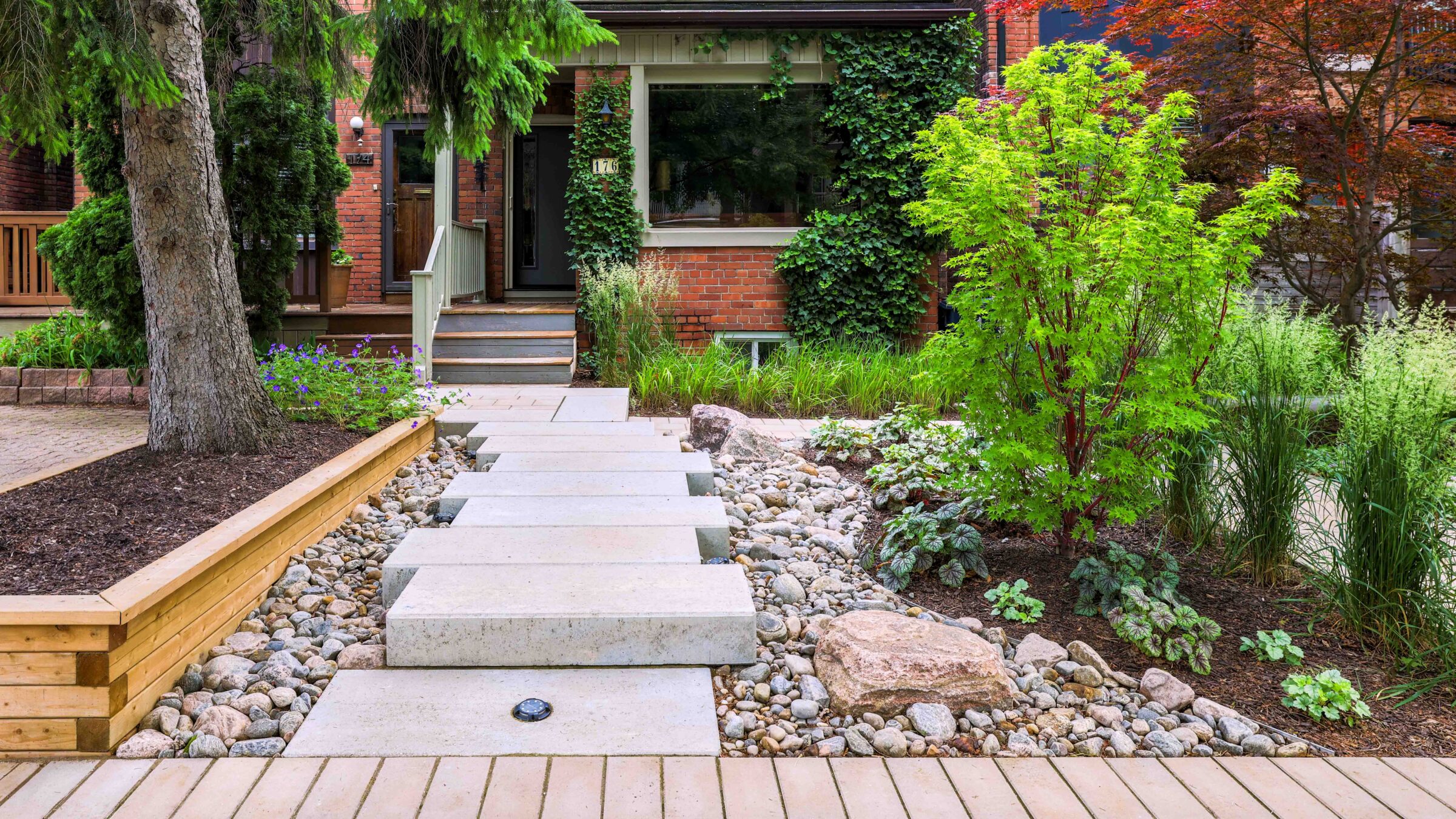 The front of a home featuring a custom stone path and bushes.