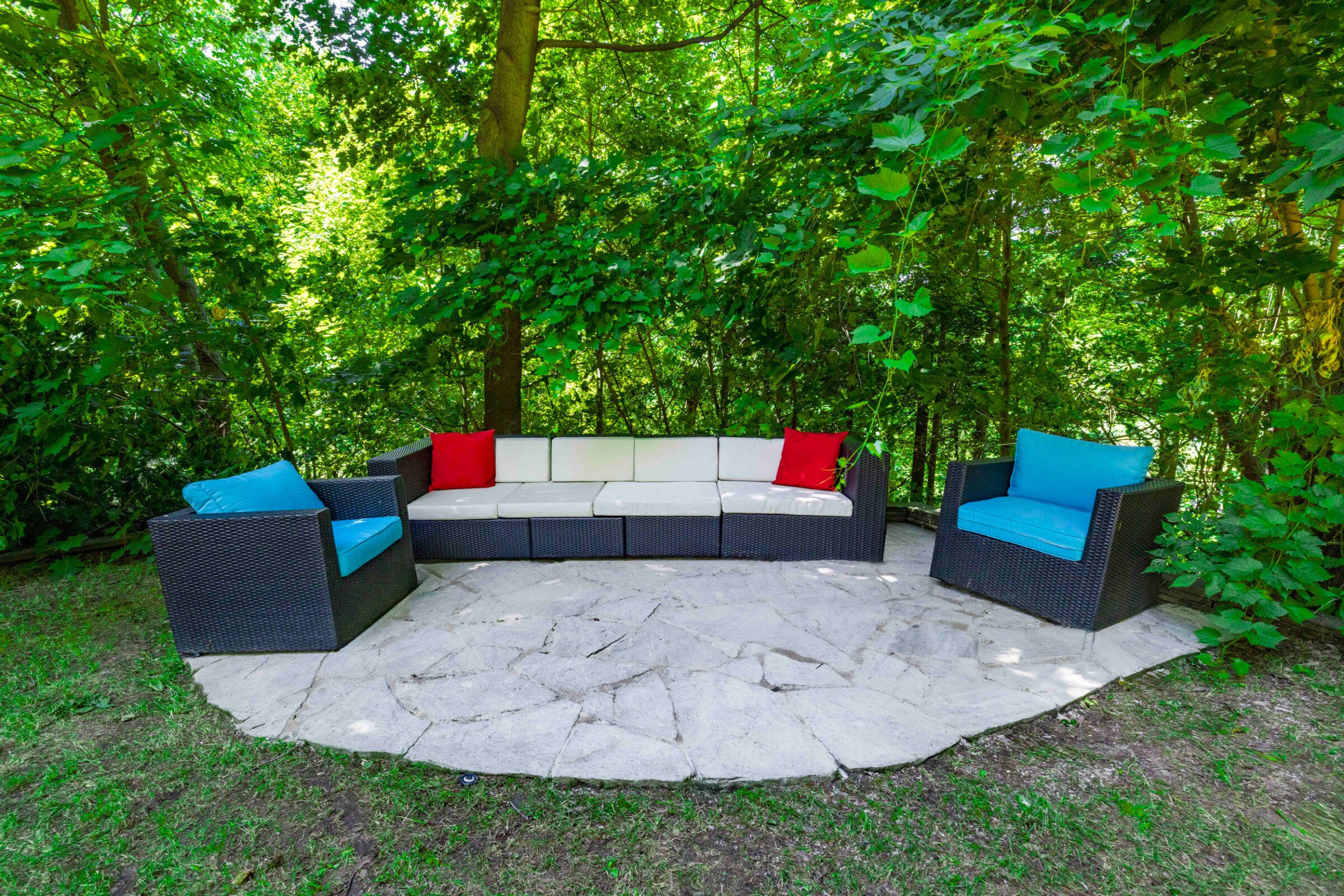 Backyard retreat design in Toronto featuring outdoor seating on a custom stone patio.