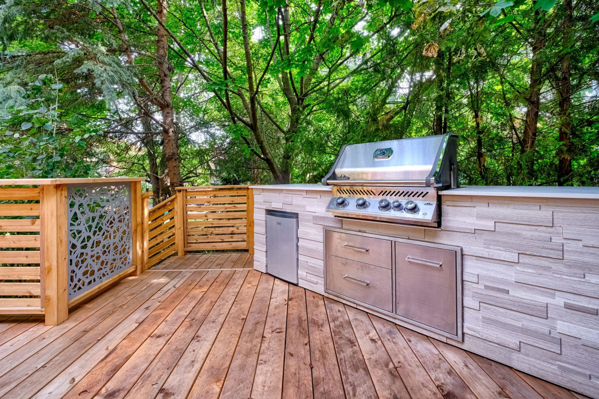 Cedar deck with built-in outdoor kitchen, stainless grill, and decorative privacy panel