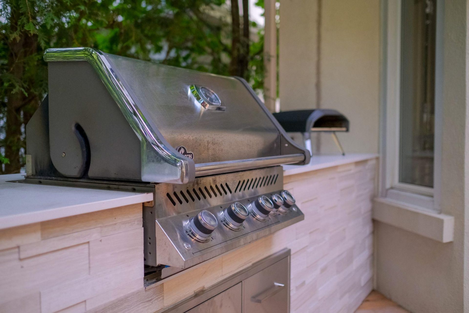 Close-up of stainless steel built-in grill on a stone outdoor kitchen counter
