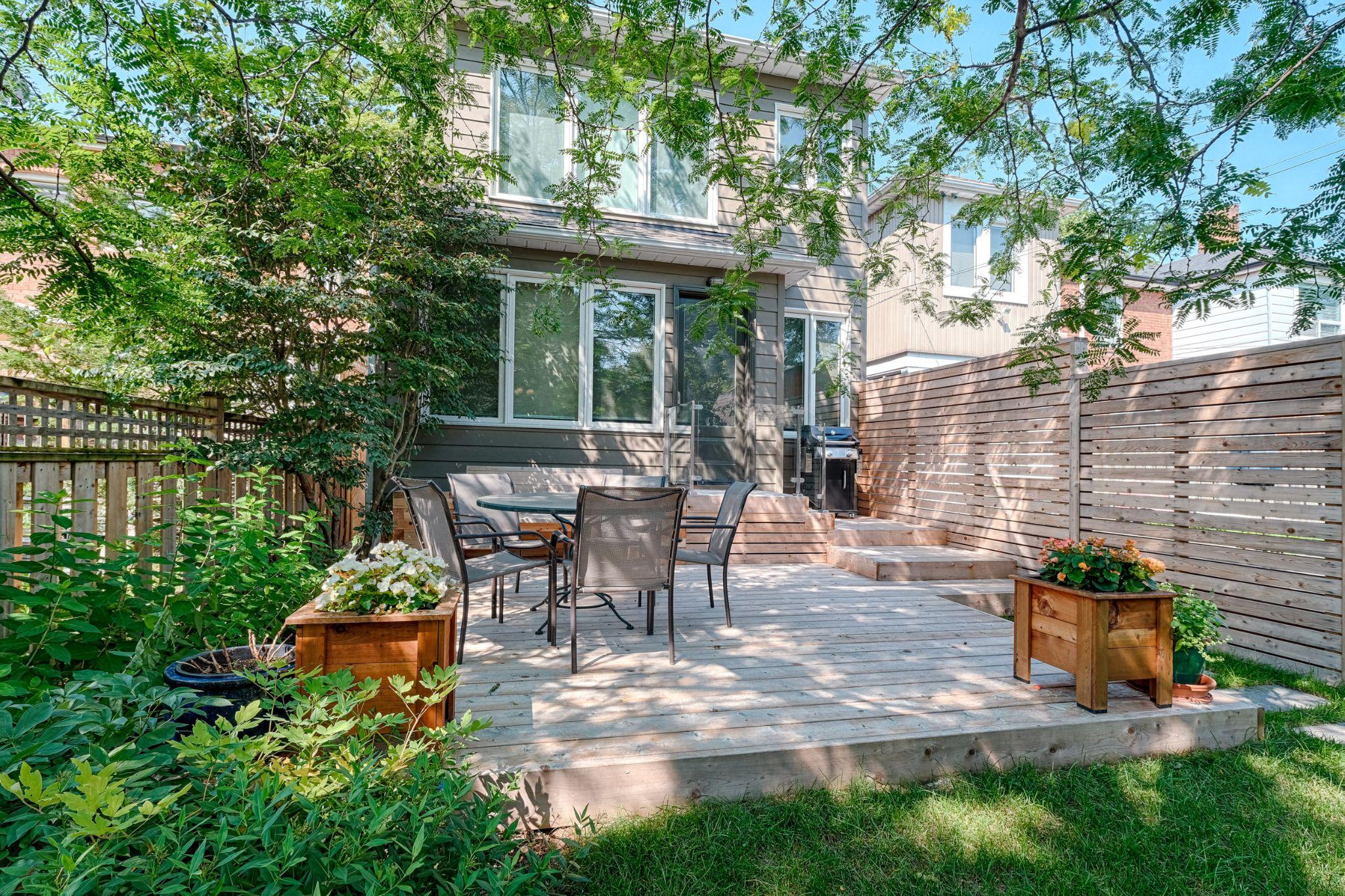 Ground-level cedar deck with dining set, raised planters, and horizontal privacy fence