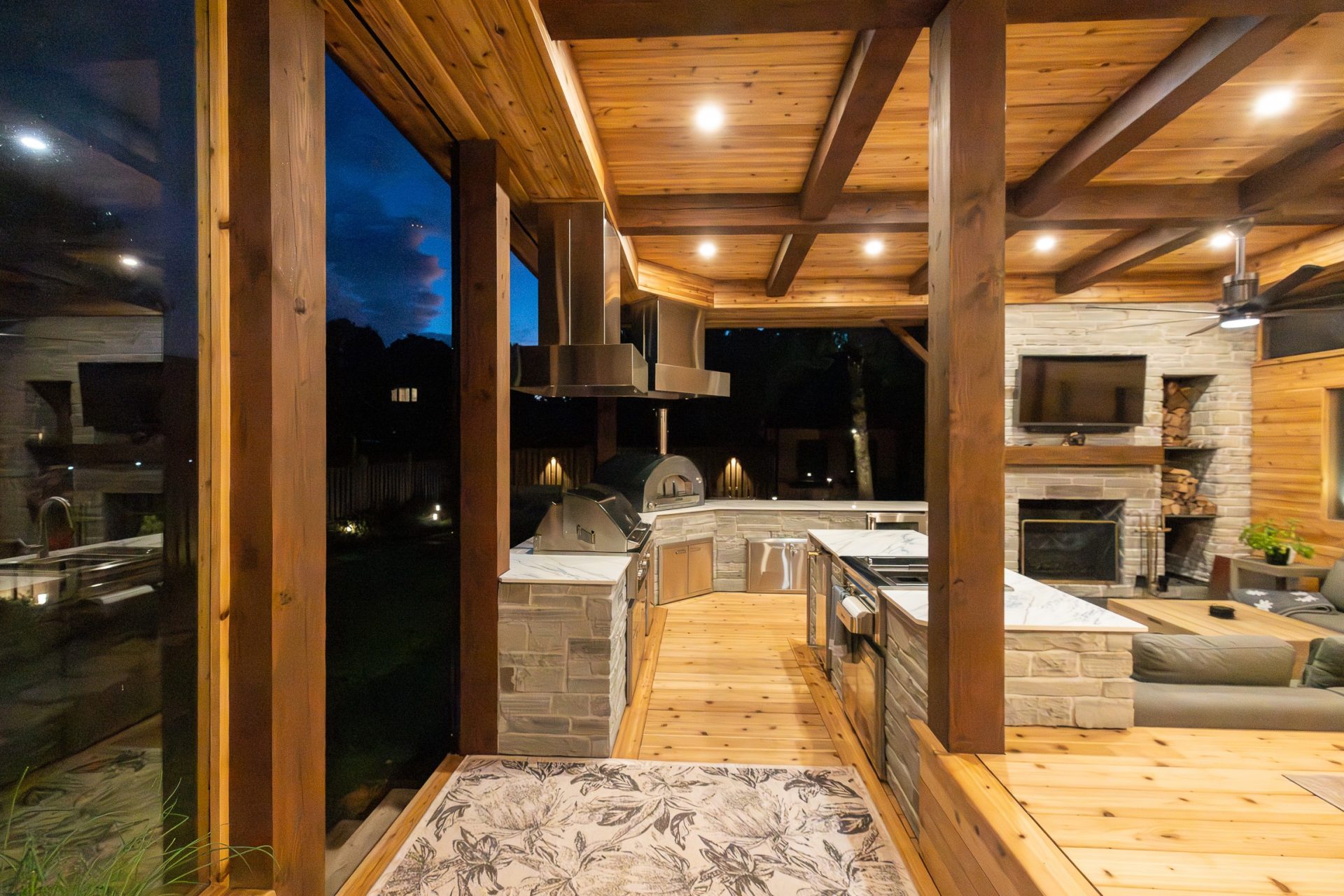 Luxury covered outdoor kitchen in Toronto with stone veneer, built-in grill, and outdoor fireplace.