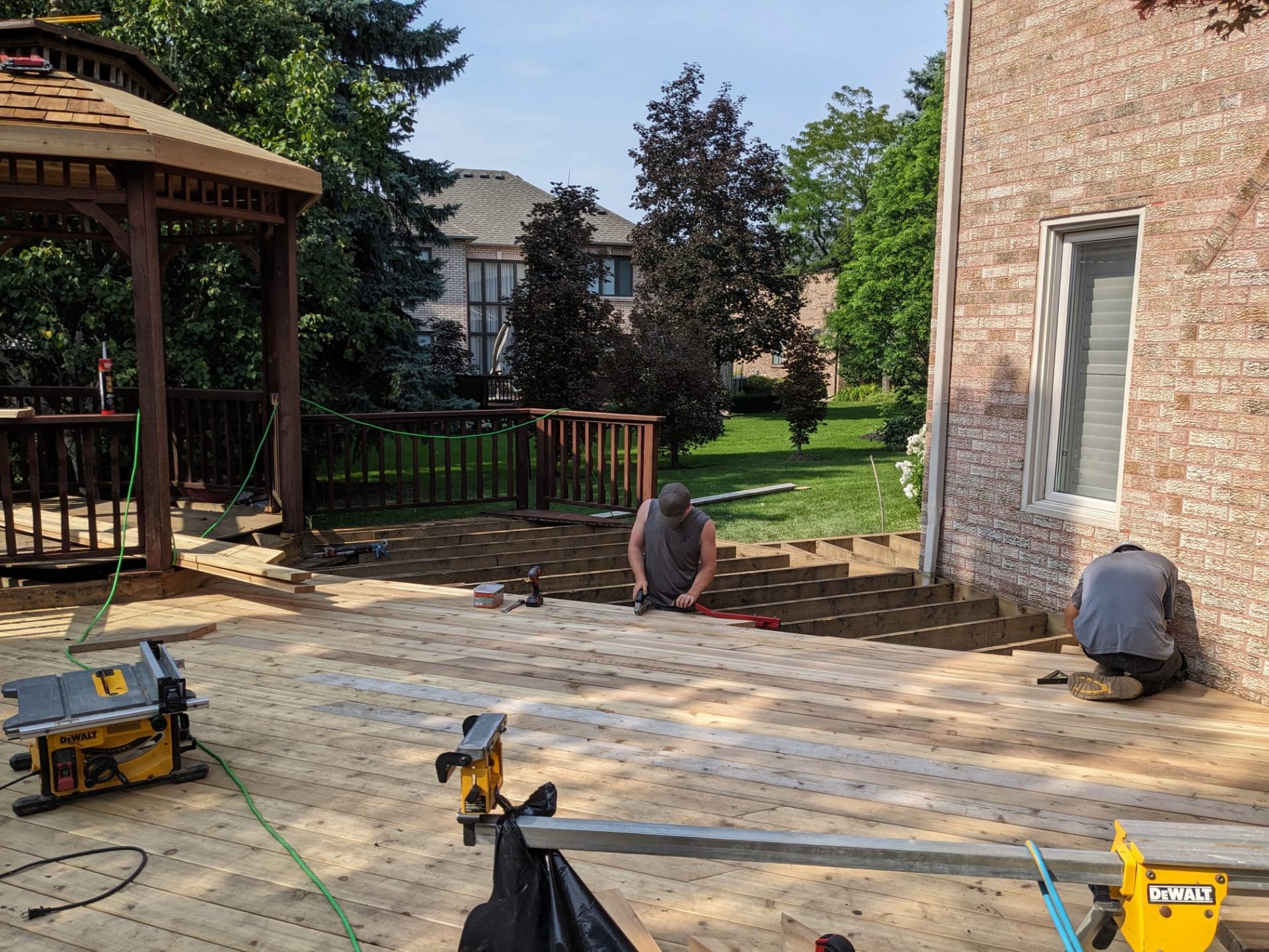 Carpenters installing wood decking boards during a backyard deck renovation project.